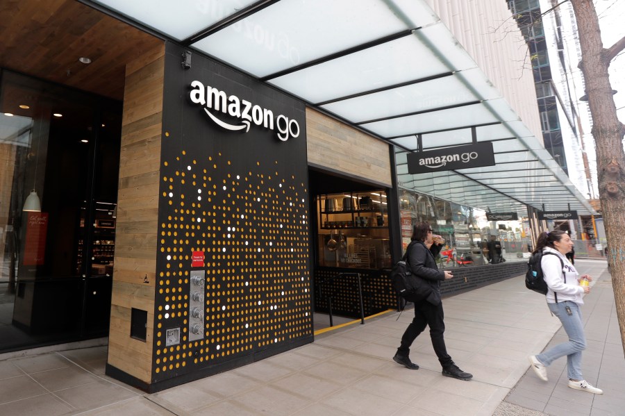 In this March 4, 2020 file photo, people walk out of an Amazon Go store, in Seattle. Amazon said Wednesday, April 21, 2021 that it is rolling out its pay-by-palm technology to some of its Whole Foods supermarkets. The technology, called Amazon One, lets shoppers scan the palm of their hand and connect it to their credit card or Amazon accounts. (AP Photo/Ted S. Warren, File)