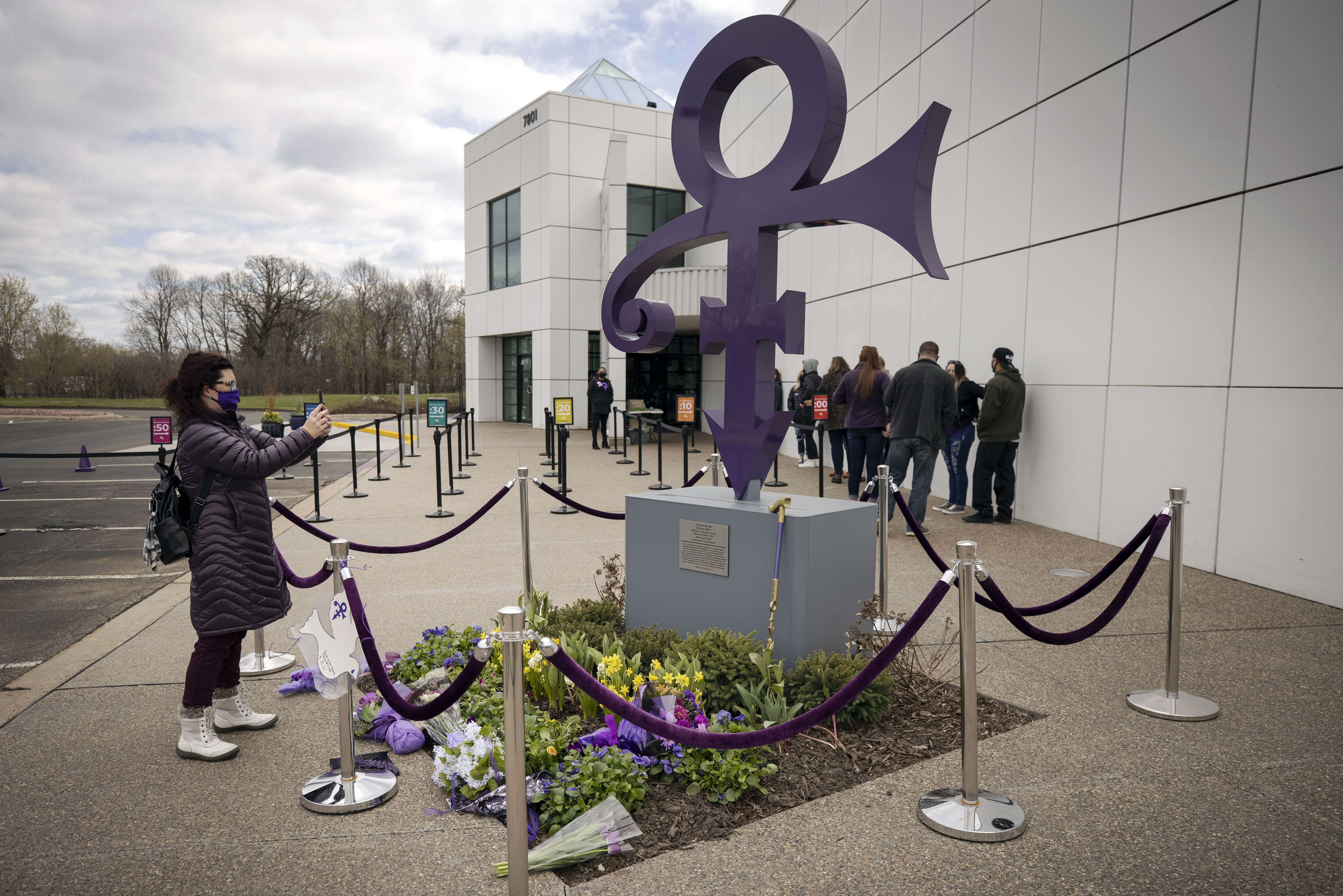 A fan takes a photo of a memorial on April 21, 2021 as others line up to go into Paisley Park in Chanhassen, Minn., on the fifth anniversary of Prince's death. (Stacy Bengs/Associated Press)