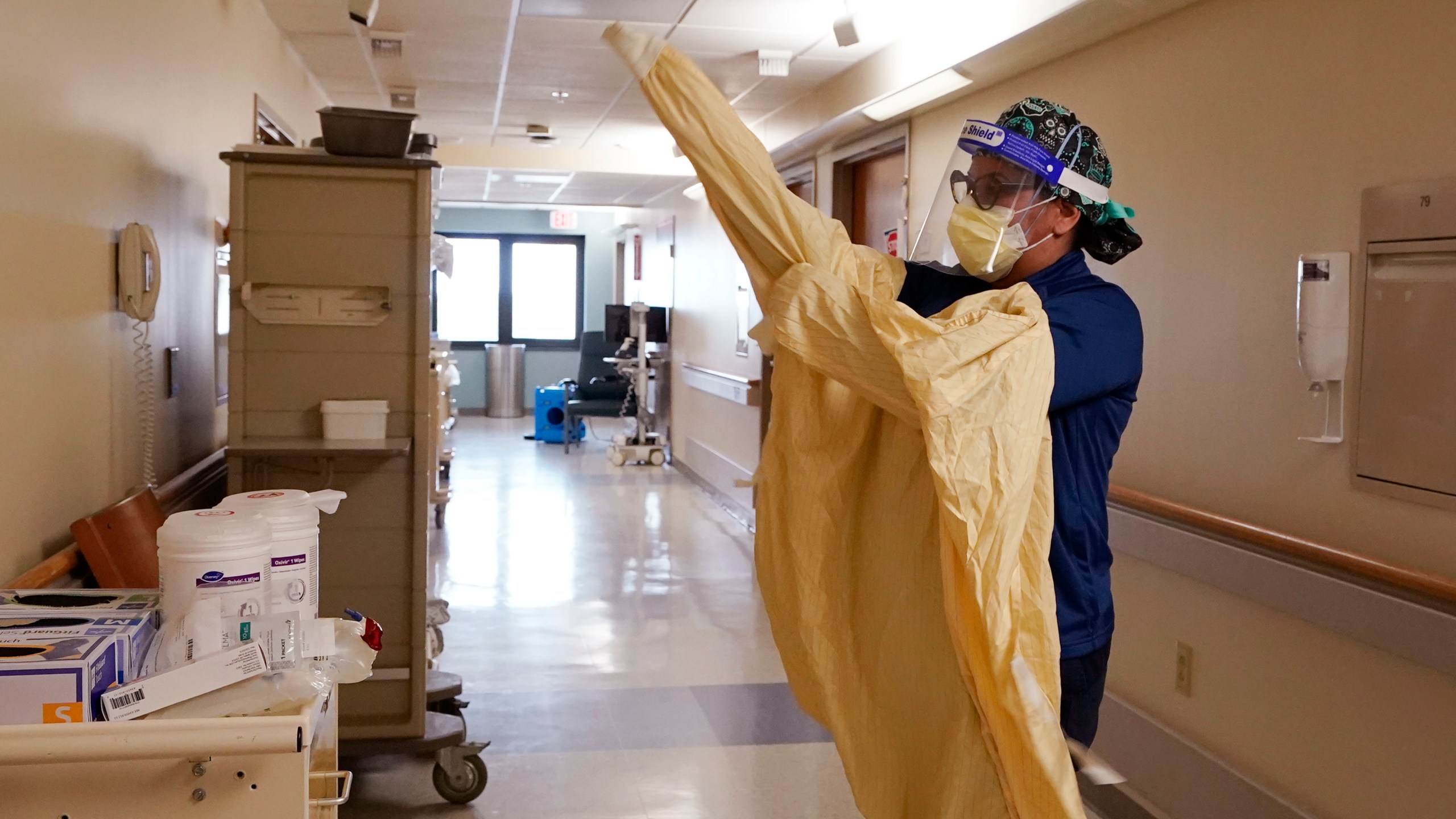 Registered Nurse Monica Quintana dons protective gear before entering a room at the William Beaumont hospital, April 21, 2021 in Royal Oak, Mich. (AP Photo/Carlos Osorio)