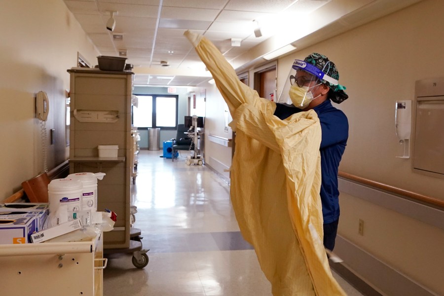 Registered Nurse Monica Quintana dons protective gear before entering a room at the William Beaumont hospital, April 21, 2021 in Royal Oak, Mich. (AP Photo/Carlos Osorio)