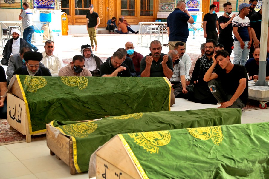 Mourners pray near the coffins of coronavirus patients who were killed in a hospital fire in Iraq, April 25, 2021. (AP Photo/Anmar Khalil)