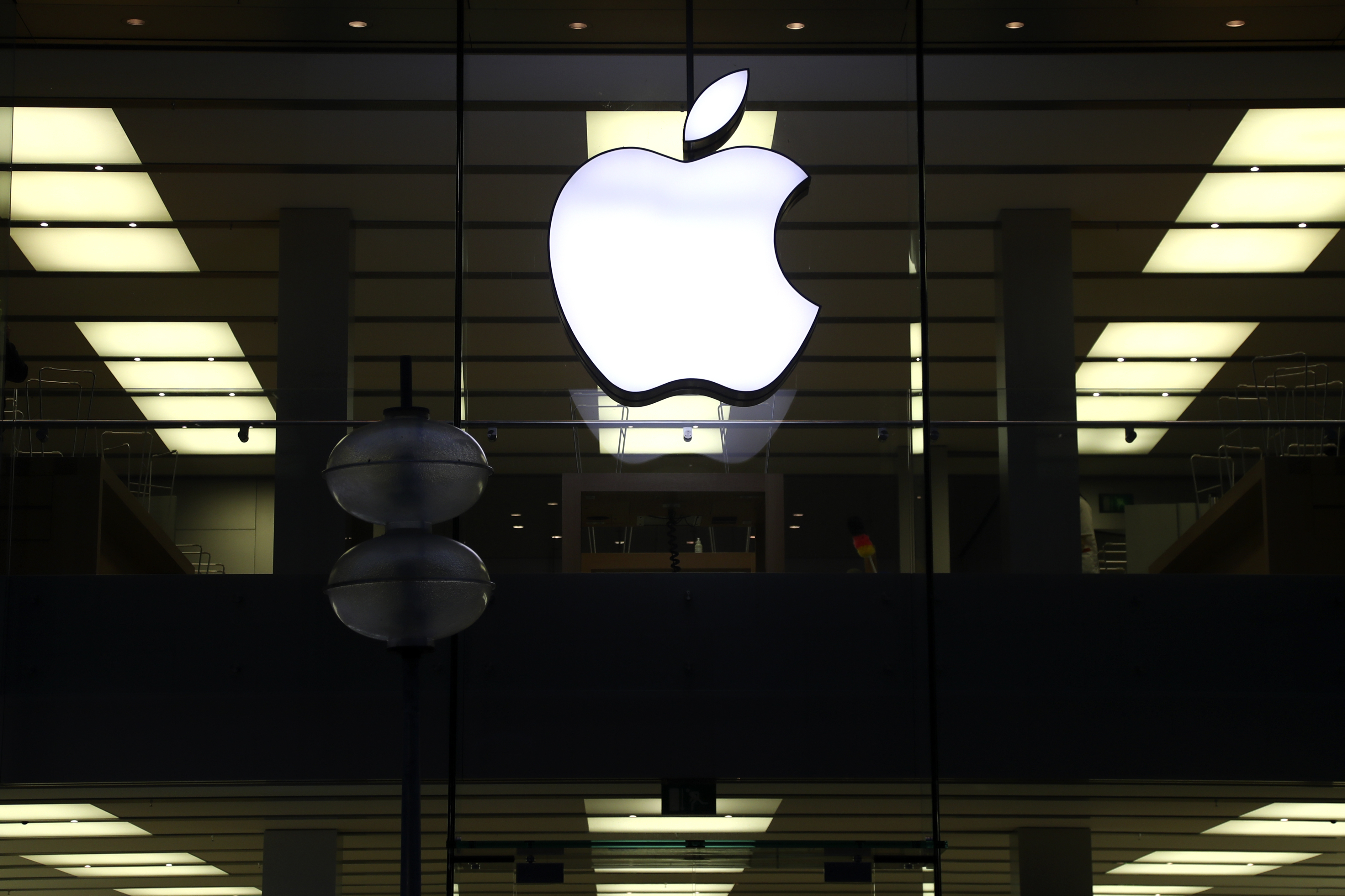 This Dec. 16, 2020 file photo shows an illuminated Apple logo at a store in Munich, Germany. Apple is following through on its pledge to crack down Facebook and other snoopy apps that secretly shadow people on their iPhones to help sell more advertising. The new privacy feature, dubbed “App Tracking Transparency,” rolled out Monday, April 26, 2021, as part of an update to the operating system powering the iPhone and iPad. (AP Photo/Matthias Schrader, File)