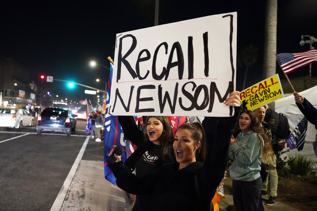 In this Nov. 21, 2020, file photo, demonstrators shout slogans while carrying a sign calling for a recall on Gov. Gavin Newsom during a protest against a stay-at-home order amid the COVID-19 pandemic in Huntington Beach, Calif. (AP Photo/Marcio Jose Sanchez, File)