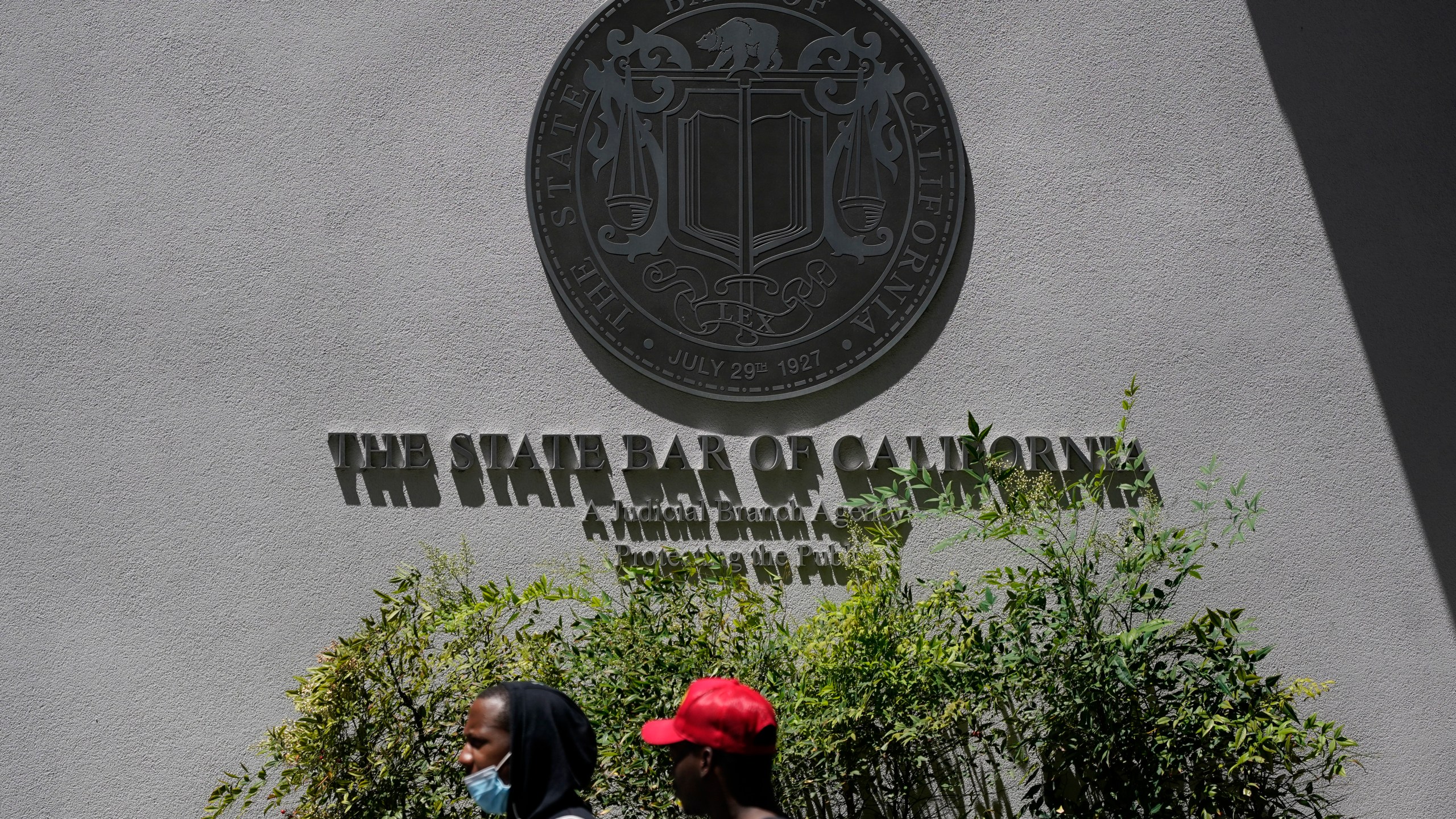 People walk past the entrance of The State Bar of California office Thursday, April 29, 2021, in Los Angeles. (AP Photo/Ashley Landis)