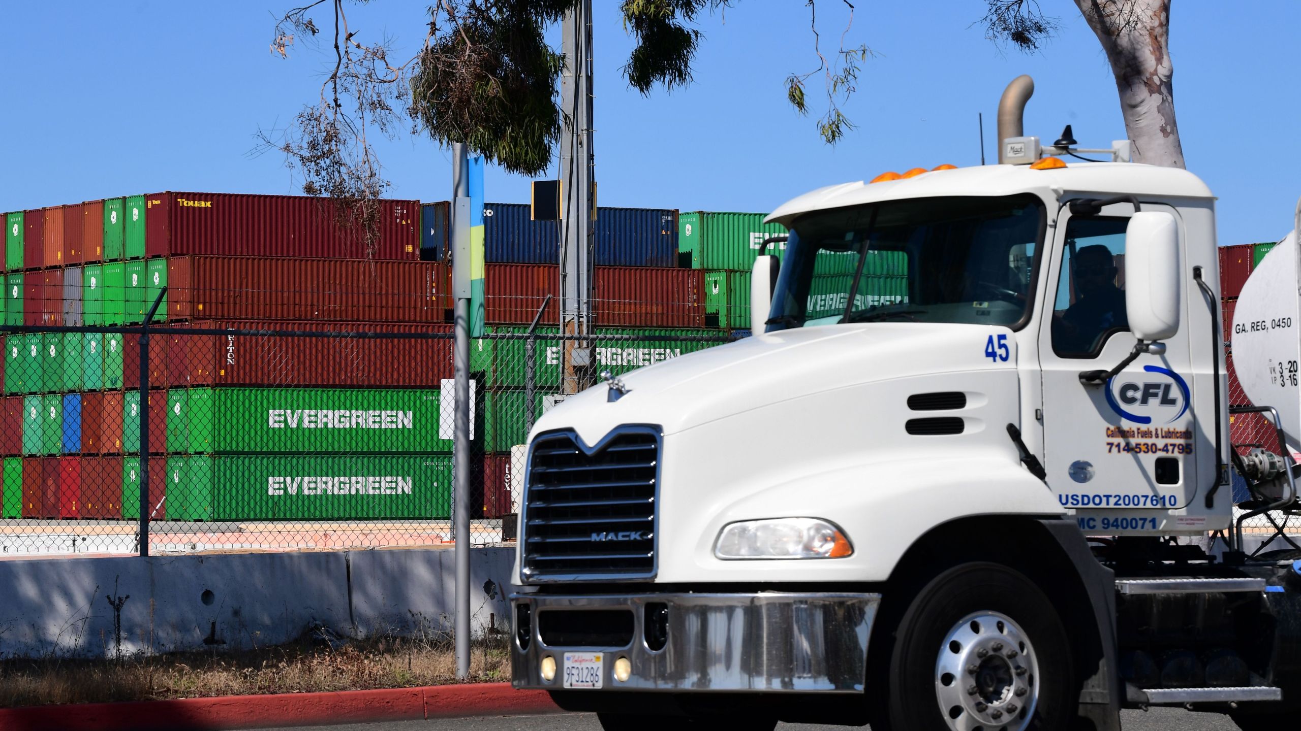 A container truck driver passes containers stacked high at the Port of Los Angeles on March 26, 2020. (Frederic J. Brown / AFP / Getty Images)