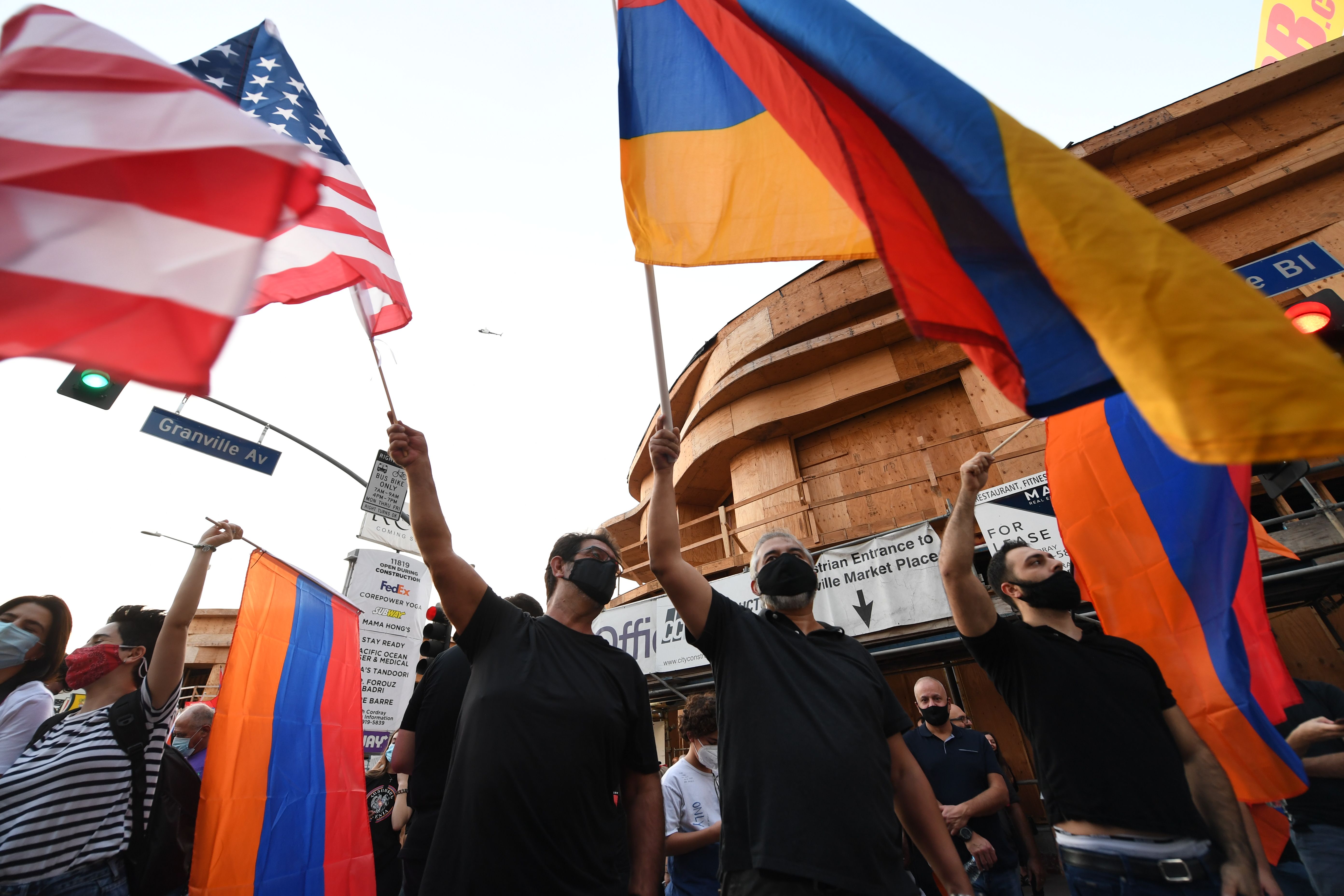 People wave U.S. and Armenian flags during a protest outside the Azerbaijani Consulate General in Los Angeles on September 30, 2020. (VALERIE MACON/AFP via Getty Images)