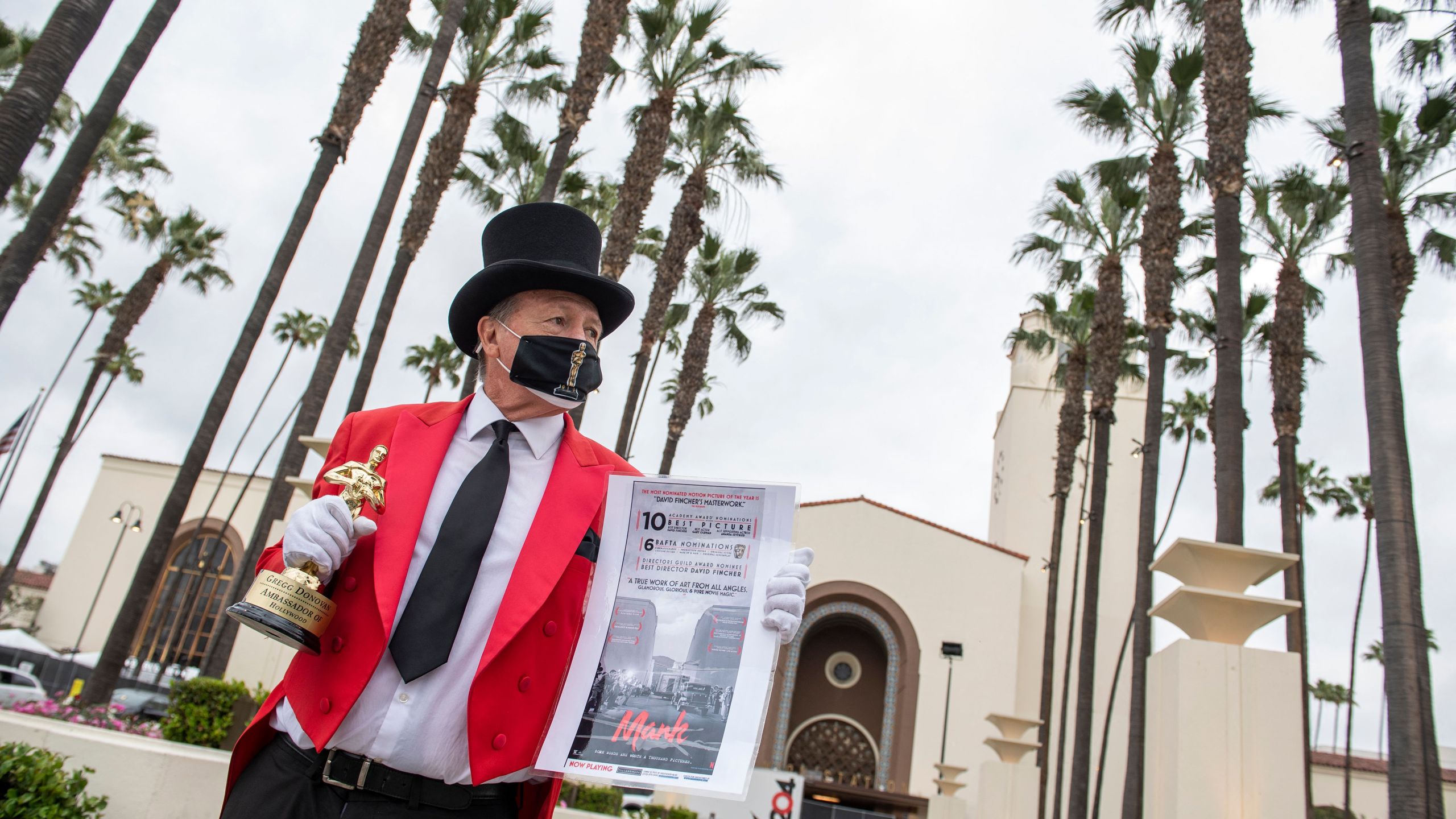 Gregg Donovan holds a fake Oscar statuette and a poster of one of the movies he believes will be a winner in front of Union Station during preparations for the 93rd Academy Awards in Los Angeles, California on April 23, 2021. (Valerie Macon/AFP via Getty Images)