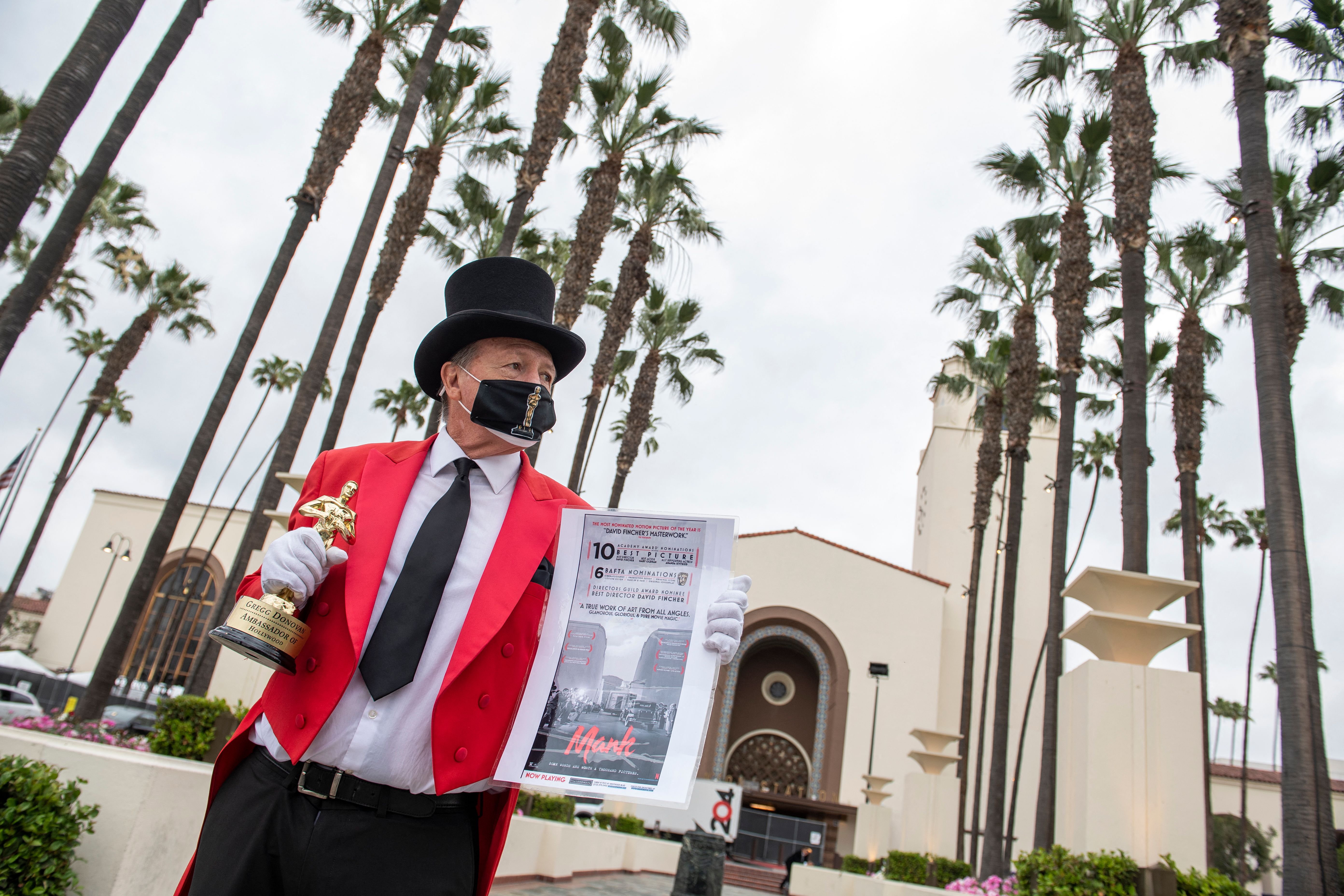 Gregg Donovan holds a fake Oscar statuette and a poster of one of the movies he believes will be a winner in front of Union Station during preparations for the 93rd Academy Awards in Los Angeles, California on April 23, 2021. (Valerie Macon/AFP via Getty Images)