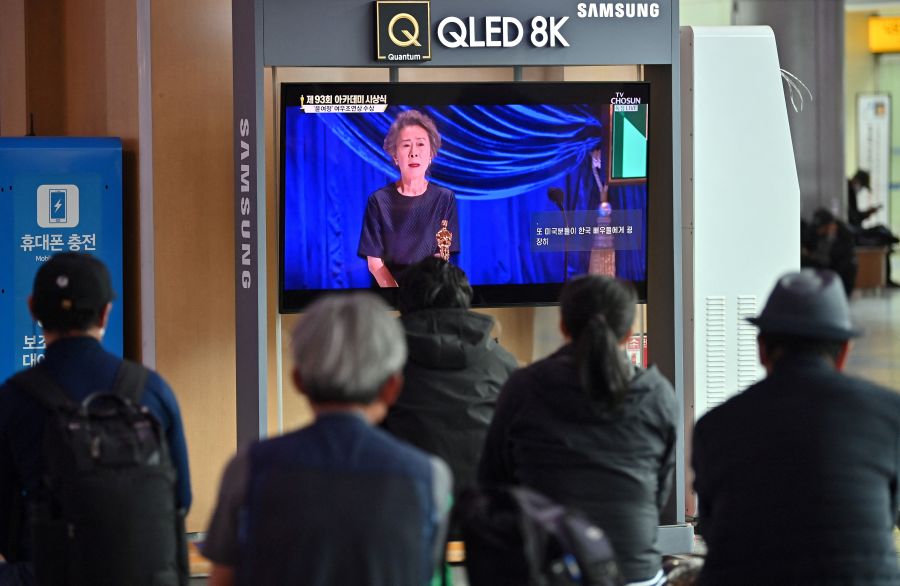 People watch a television screen broadcasting live footage of South Korea's first Oscar-winning actress Youn Yuh-jung speaking at the 93rd Academy Awards ceremony held in Los Angeles, at Seoul railway station in Seoul on April 26, 2021. (JUNG YEON-JE/AFP via Getty Images)