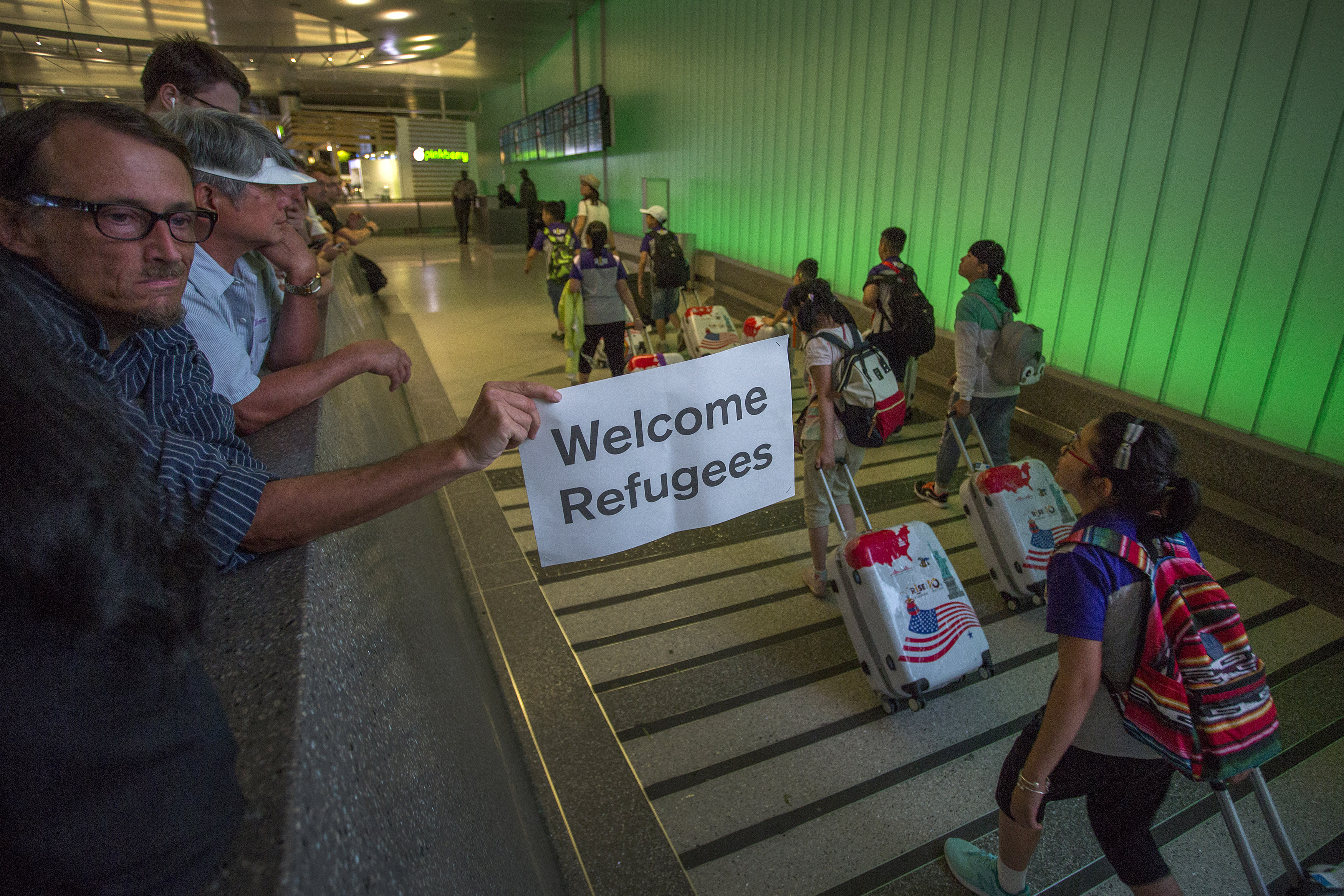 A man carries a welcome sign near arriving international travelers at LAX on the first day of the partial reinstatement of Trump's travel ban on June 29, 2017 in Los Angeles. (David McNew/Getty Images)