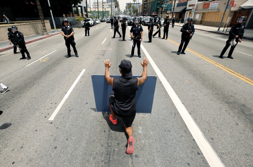 Protester Diego Martinez takes a knee in front of Los Angeles police officers in Hollywood on June 2, 2020. (Al Seib / Los Angeles Times)