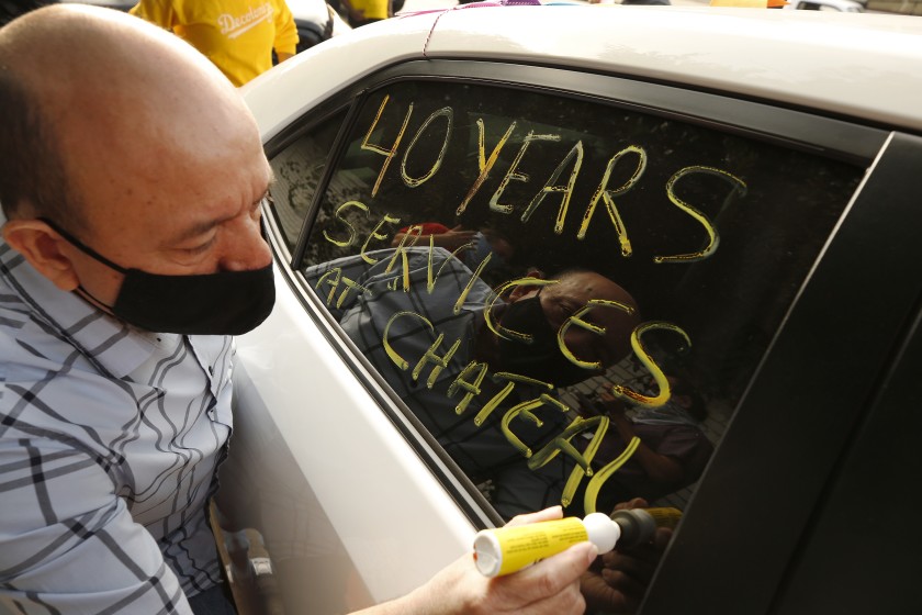 Carlos Barrera, who worked in valet parking for 40 years at the Chateau Marmont, writes messages on the window of his car in support of workers who lost their jobs at the Chateau Marmont as they form a caravan to travel from the L.A. area to Sacramento to protest in favor of a bill that would protect their jobs. (Al Seib/Los Angeles Times)