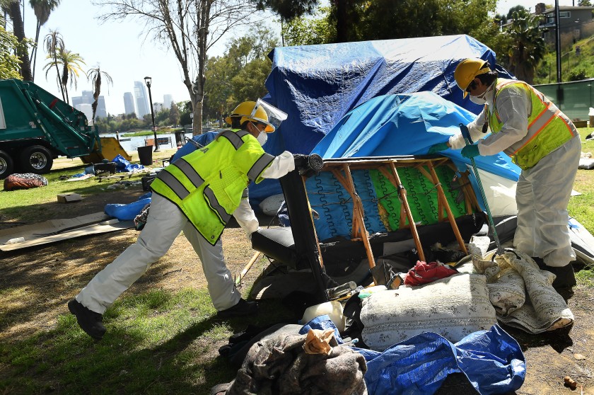 Workers remove a couch from a campsite left behind by a homeless person in Echo Park in April 2021. (Wally Skalij / Los Angeles Times)