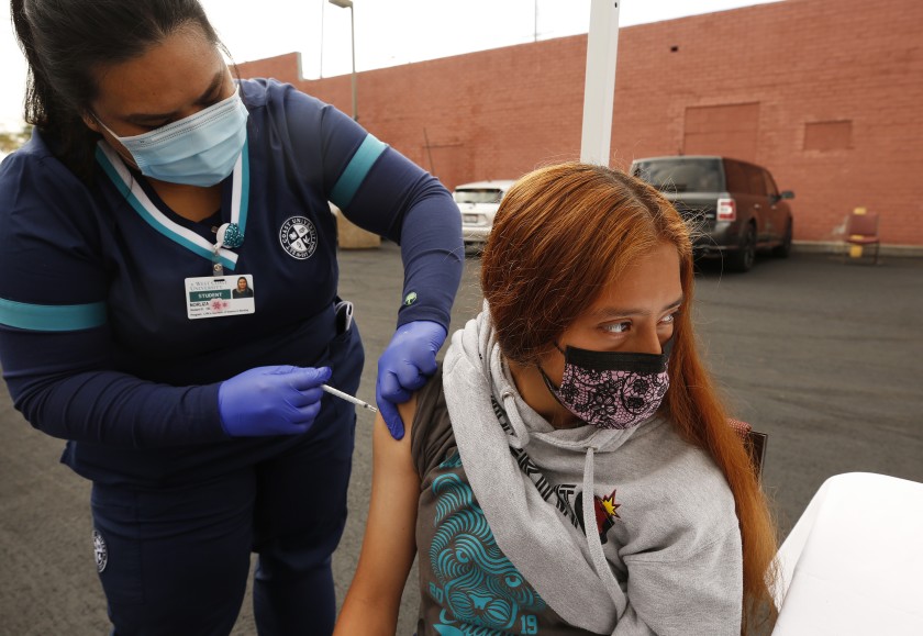 Jamilette Mota, 17, receives her Pfizer COVID-19 vaccination from student registered nurse Josselyn Solano at a walk-up mobile COVID-19 clinic in Los Angeles on April 2021. (Al Seib / Los Angeles Times)