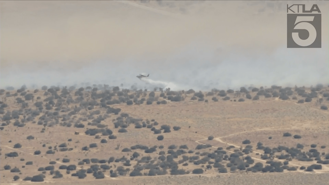 A helicopter makes a water drop on what's left of the Wee Ville Fire in Fairmont on May 20, 2021. (KTLA)