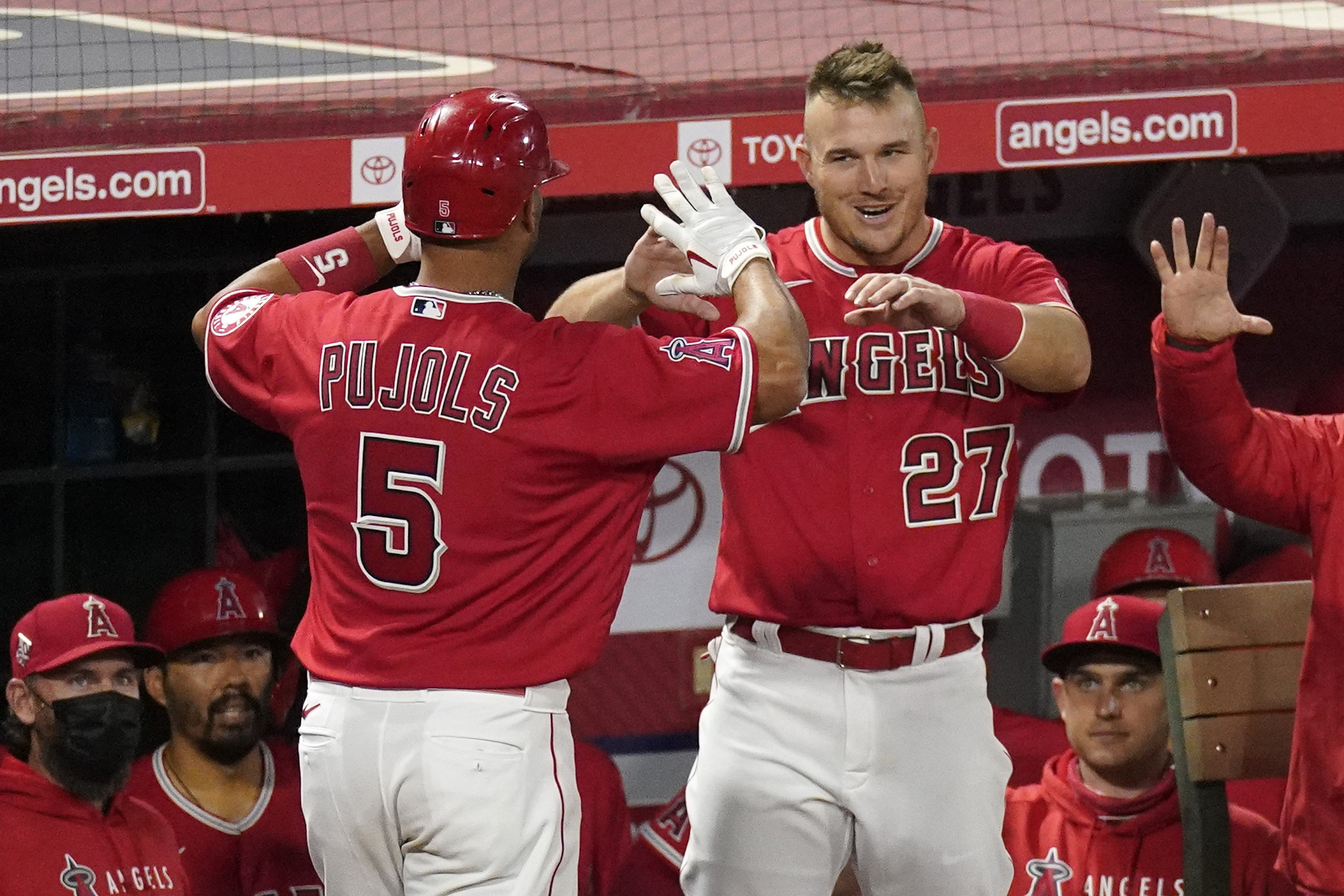 Los Angeles Angels' Albert Pujols, left, is congratulated by Mike Trout after hitting a solo home run during the seventh inning of a baseball game against the Texas Rangers in Anaheim on April 20, 2021. (Mark J. Terrill / Associated Press)