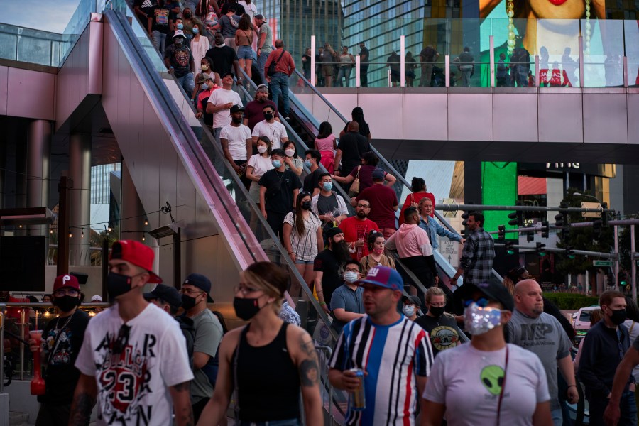 People ride an escalator along the Las Vegas Strip, Saturday, April 24, 2021, in Las Vegas. The tourism-dependent city is bustling again after casino capacity limits were raised Saturday, May 1, to 80% and person-to-person distancing dropped to 3 feet (0.9 meters). (AP Photo/John Locher)