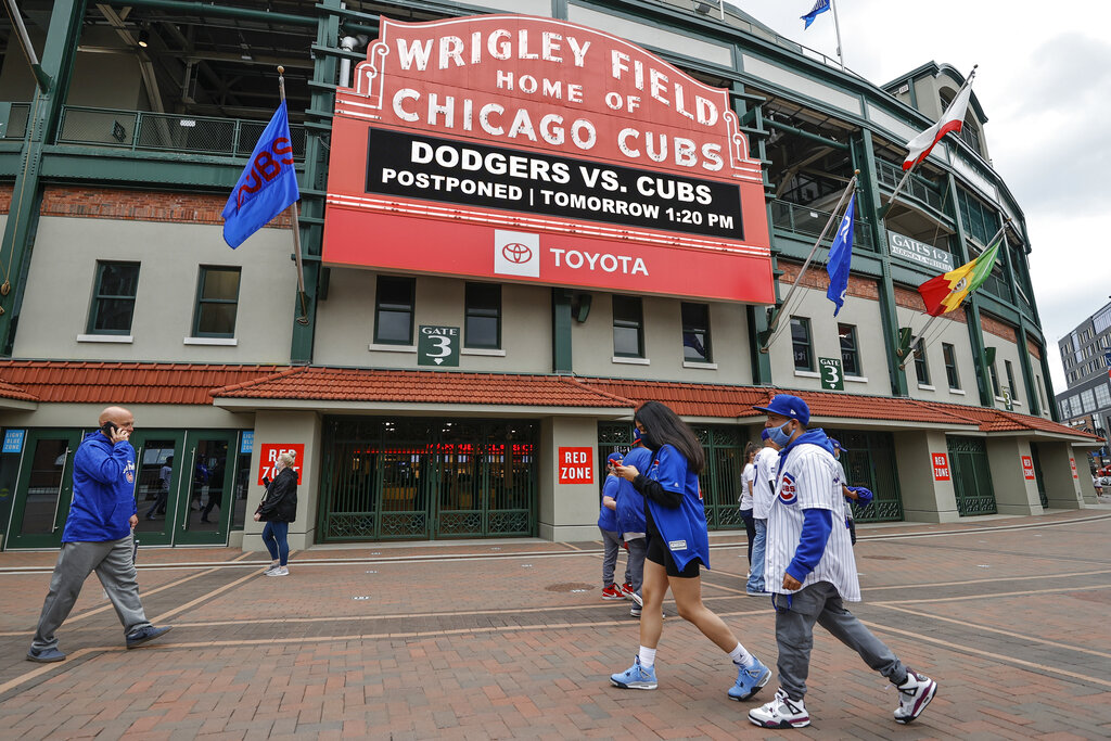 Fans walk outside Wrigley Field as a baseball game between the Chicago Cubs and the Los Angels Dodgers was postponed due to the forecast of inclement weather, Monday, May 3, 2021, in Chicago. (AP Photo/Kamil Krzaczynski)