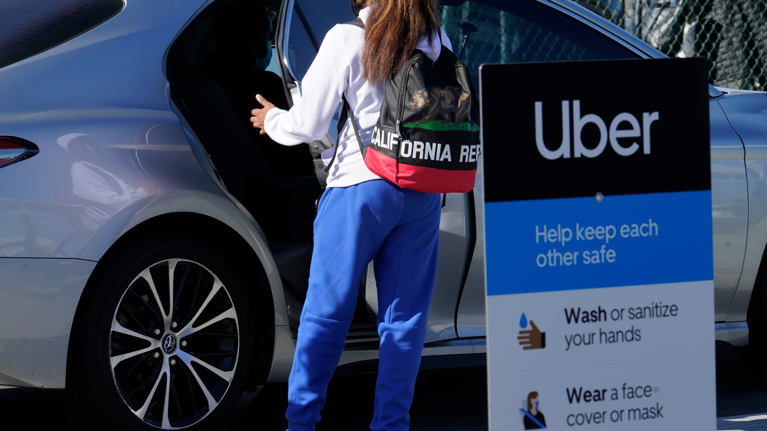 In this Nov. 13, 2020, file photo, a traveler rides in the back of an Uber vehicle at Los Angeles International Airport. (AP Photo/Damian Dovarganes, File)