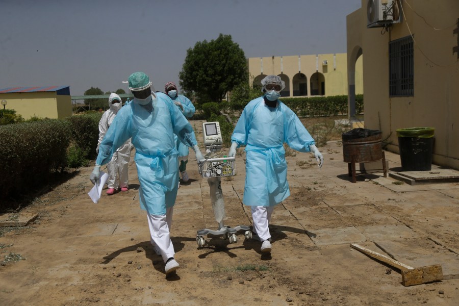 Doctors caring with COVID-19 patients ferry medical equipment, at the Farcha provincial hospital in N'Djamena, Chad, Friday April 30, 2021. (AP Photo/Sunday Alamba)