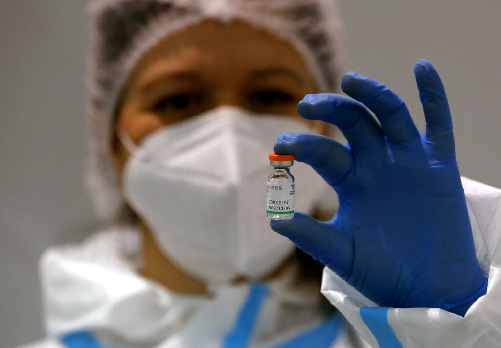 In this Tuesday, Jan. 19, 2021 file photo, a medical worker poses with a vial of the Sinopharm's COVID-19 vaccine in Belgrade, Serbia. (AP Photo/Darko Vojinovic, file)