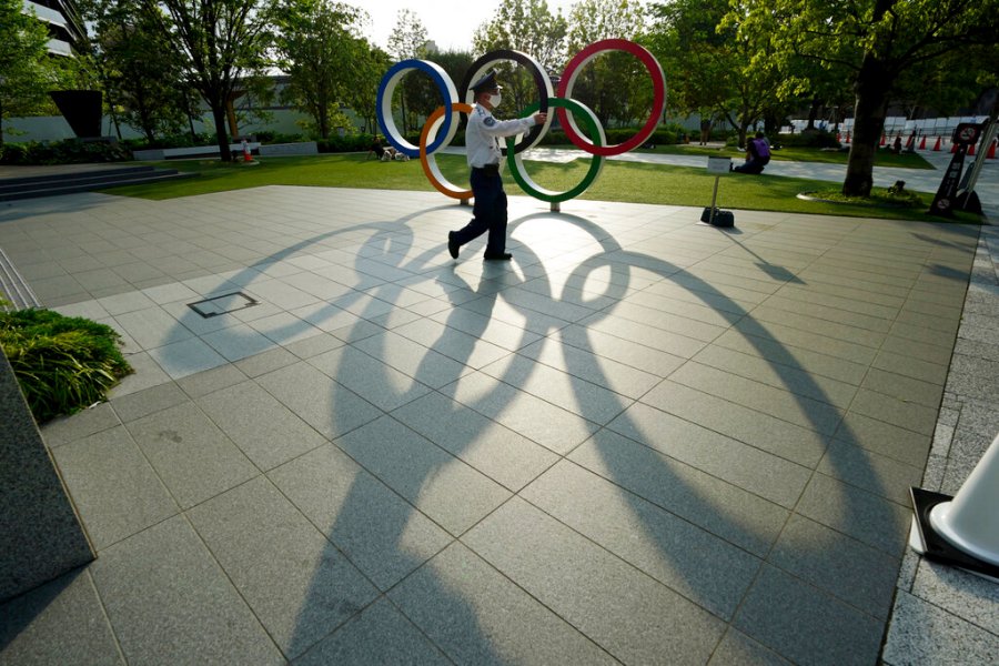 A security guard wearing a protective mask to help curb the spread of the coronavirus walks in front of the Olympic Rings on May 9, 2021, in Tokyo. (AP Photo/Eugene Hoshiko)