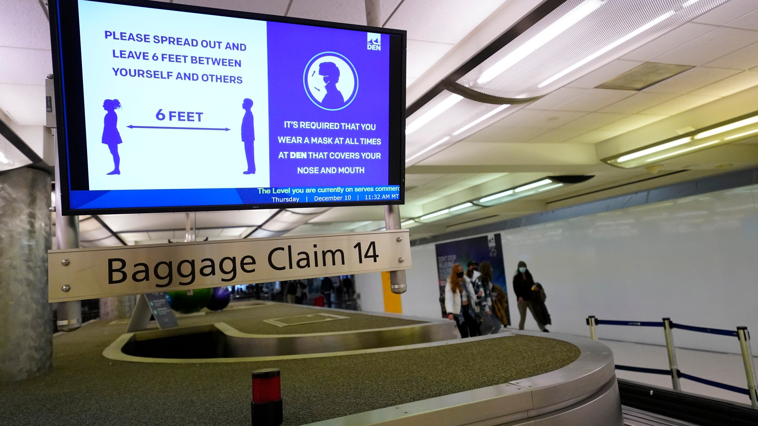 In this Dec. 10, 2020, file photo, an electronic sign warns travelers to maintain social distance in the terminal of Denver International Airport in Denver. Federal officials said Monday, May 10, 2021 they are pursuing civil penalties against two more passengers for interfering with airline crews, the latest in a surge of such cases in recent months. (AP Photo/David Zalubowski, File)