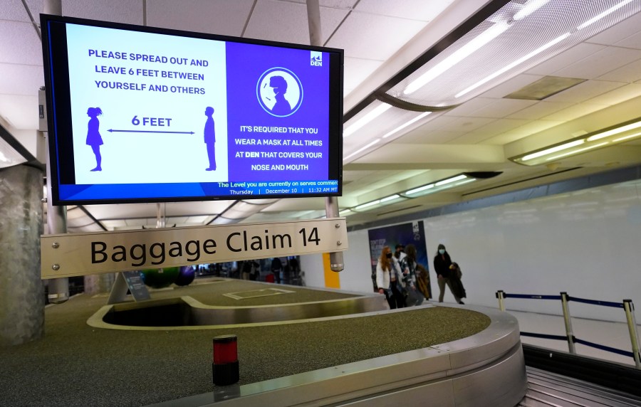 In this Dec. 10, 2020, file photo, an electronic sign warns travelers to maintain social distance in the terminal of Denver International Airport in Denver. Federal officials said Monday, May 10, 2021 they are pursuing civil penalties against two more passengers for interfering with airline crews, the latest in a surge of such cases in recent months. (AP Photo/David Zalubowski, File)