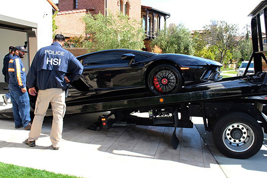 This photo provided by U.S. Immigration and Customs Enforcement shows a special agent with HSI Los Angeles's El Camino Real Financial Crimes Task Force seize a Ferrari from Orange County businessman Mustafa Qadiri on April 7, 2021, in Santa Ana, Calif. (U.S. Immigration and Customs Enforcement via AP)