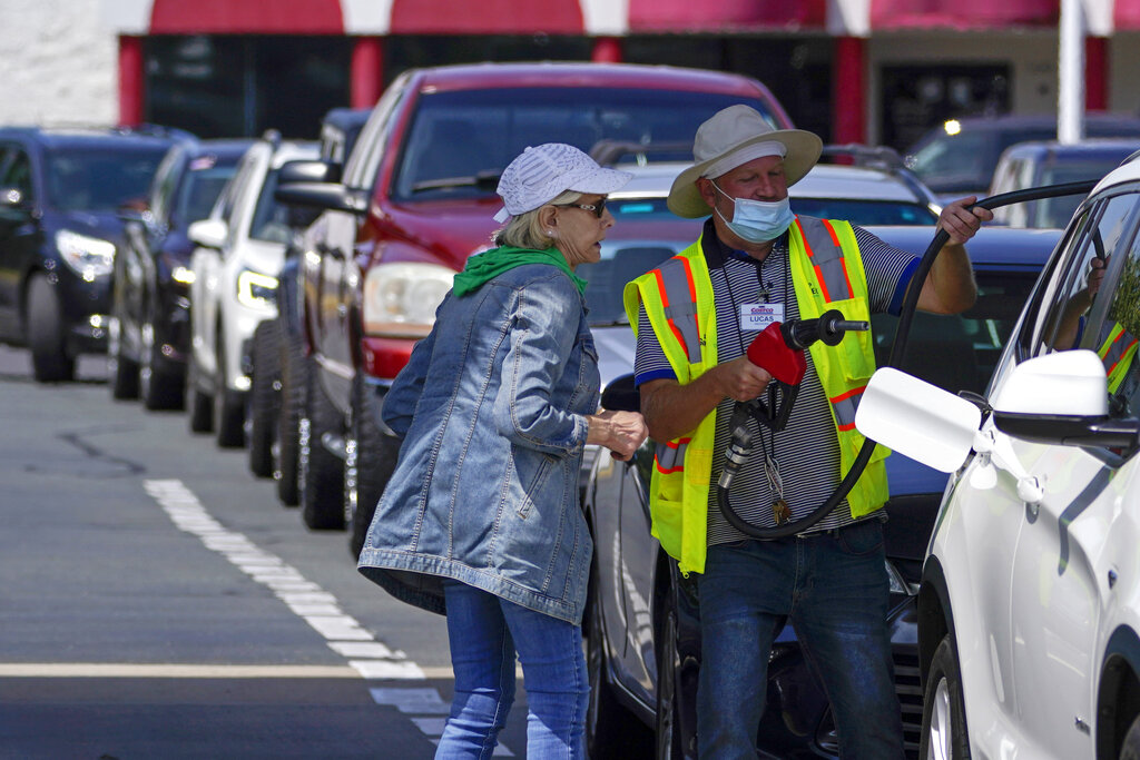 A customer helps pumping gas at Costco, as other wait in line, on Tuesday, May 11, 2021, in Charlotte, N.C. (AP Photo/Chris Carlson)