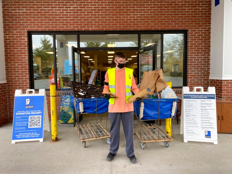 In this undated photo provided by Goodwill Northern New England, a donation attendant working for Goodwill Northern New England at the Westbrook, Maine, store looks at a broken picture frame and a broken cat scratching post. (Heather Steeves/Goodwill Northern New England via AP)