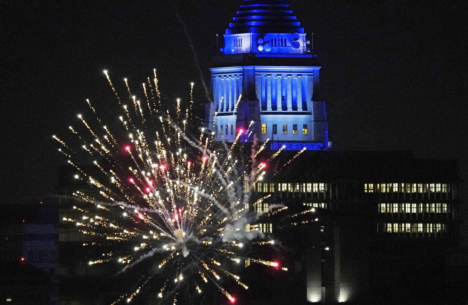 Los Angeles City Hall is illuminated with dark blue lights as Dodgers fans celebrate with fireworks on Sunset Boulevard after watching Game 6 of the World Series on Oct. 27, 2020. (Damian Dovarganes / Associated Press)