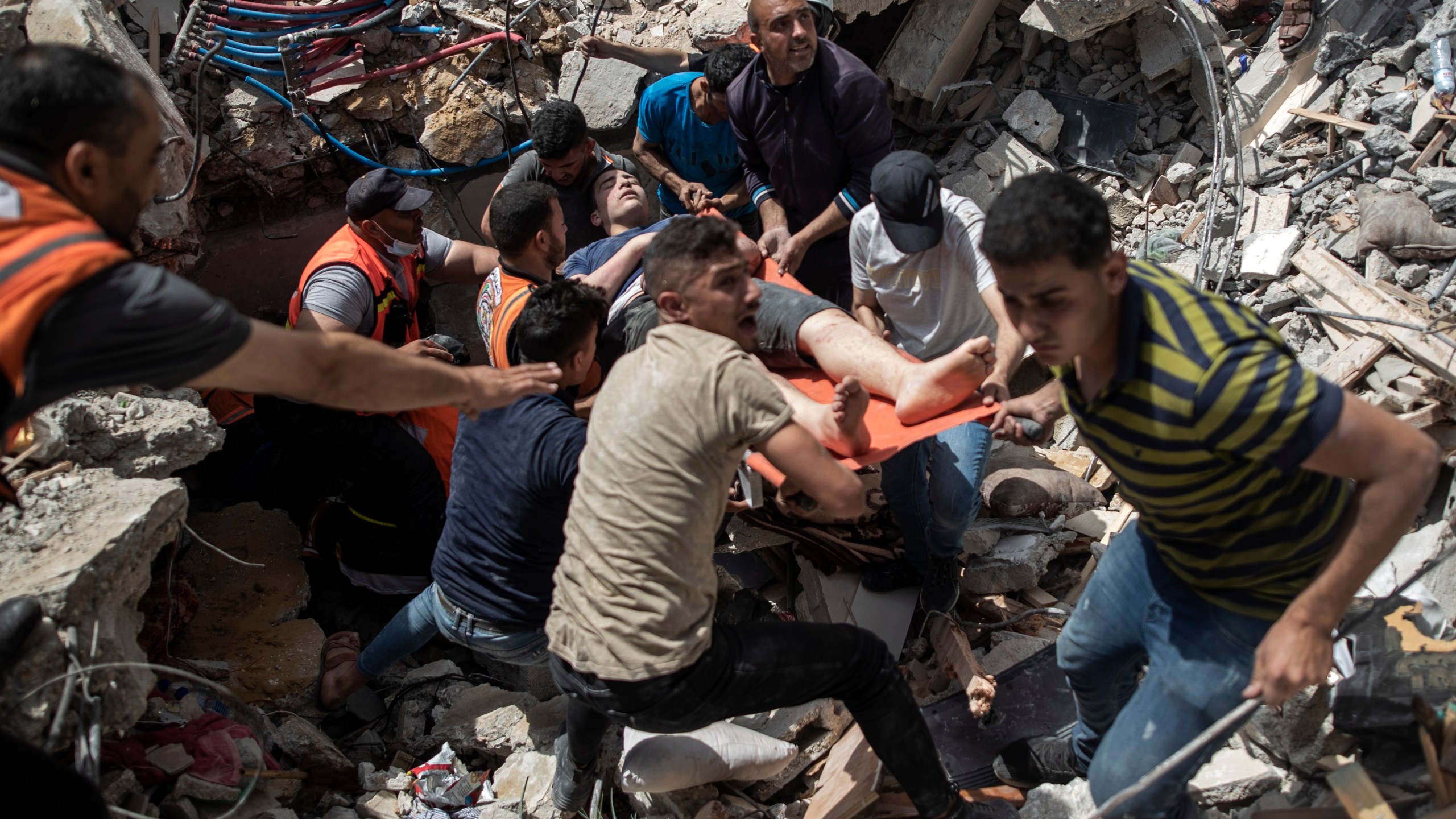 Palestinian rescue a survivor from under the rubble of a destroyed residential building following deadly Israeli airstrikes in Gaza City, Sunday, May 16, 2021. The Israeli airstrikes flattened three buildings and killed at least 26 people Sunday, medics said, making it the deadliest single attack since heavy fighting broke out between Israel and the territory's militant Hamas rulers nearly a week ago. (AP Photo/Khalil Hamra)