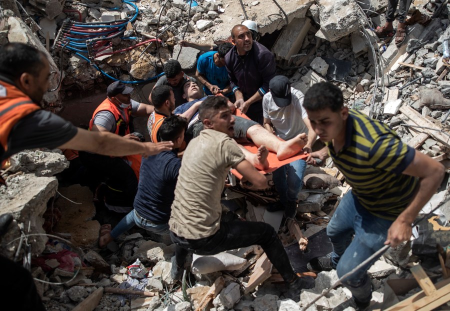 Palestinian rescue a survivor from under the rubble of a destroyed residential building following deadly Israeli airstrikes in Gaza City, Sunday, May 16, 2021. The Israeli airstrikes flattened three buildings and killed at least 26 people Sunday, medics said, making it the deadliest single attack since heavy fighting broke out between Israel and the territory's militant Hamas rulers nearly a week ago. (AP Photo/Khalil Hamra)