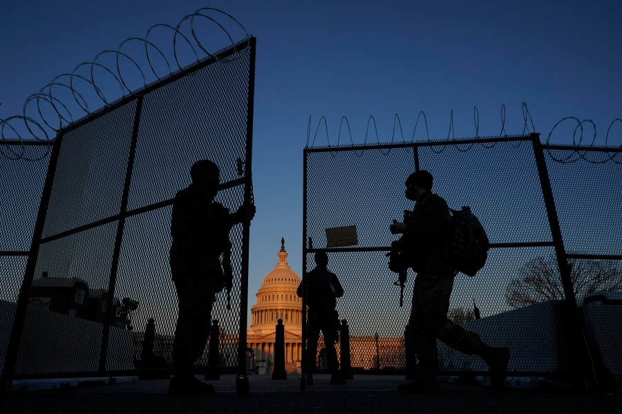 In this March 8, 2021, file photo, members of the National Guard open a gate in the razor wire topped perimeter fence around the Capitol at sunrise in Washington. (AP Photo/Carolyn Kaster, File)