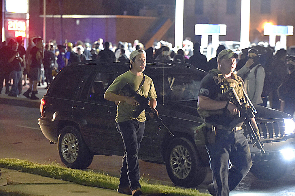 In this Aug. 25, 2020 file photo, Kyle Rittenhouse, left, with backwards cap, walks along Sheridan Road in Kenosha, Wis., with another armed civilian. (Adam Rogan/The Journal Times via AP, File)