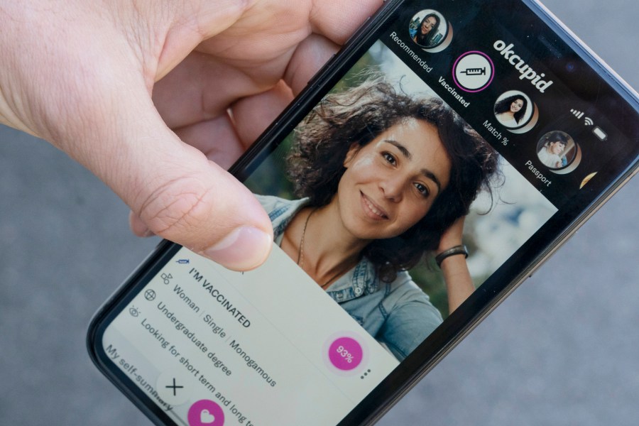 A sample page on the OkCupid app is held for a photograph showing the "I'm vaccinated," checkmark, Friday, May 21, 2021, in Washington. (AP Photo/Alex Brandon)