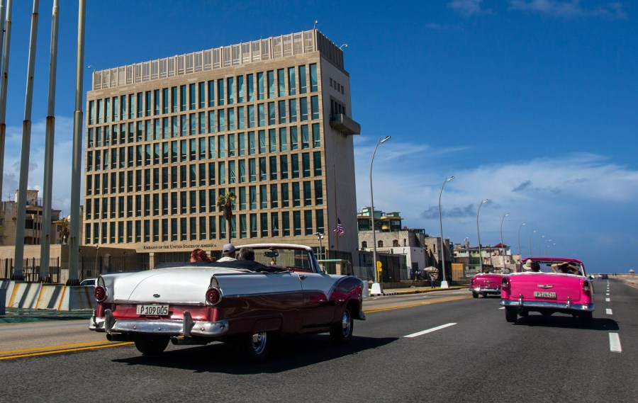 In this Oct. 3, 2017, file photo, tourists ride classic convertible cars on the Malecon beside the United States Embassy in Havana, Cuba. (AP Photo/Desmond Boylan, File)