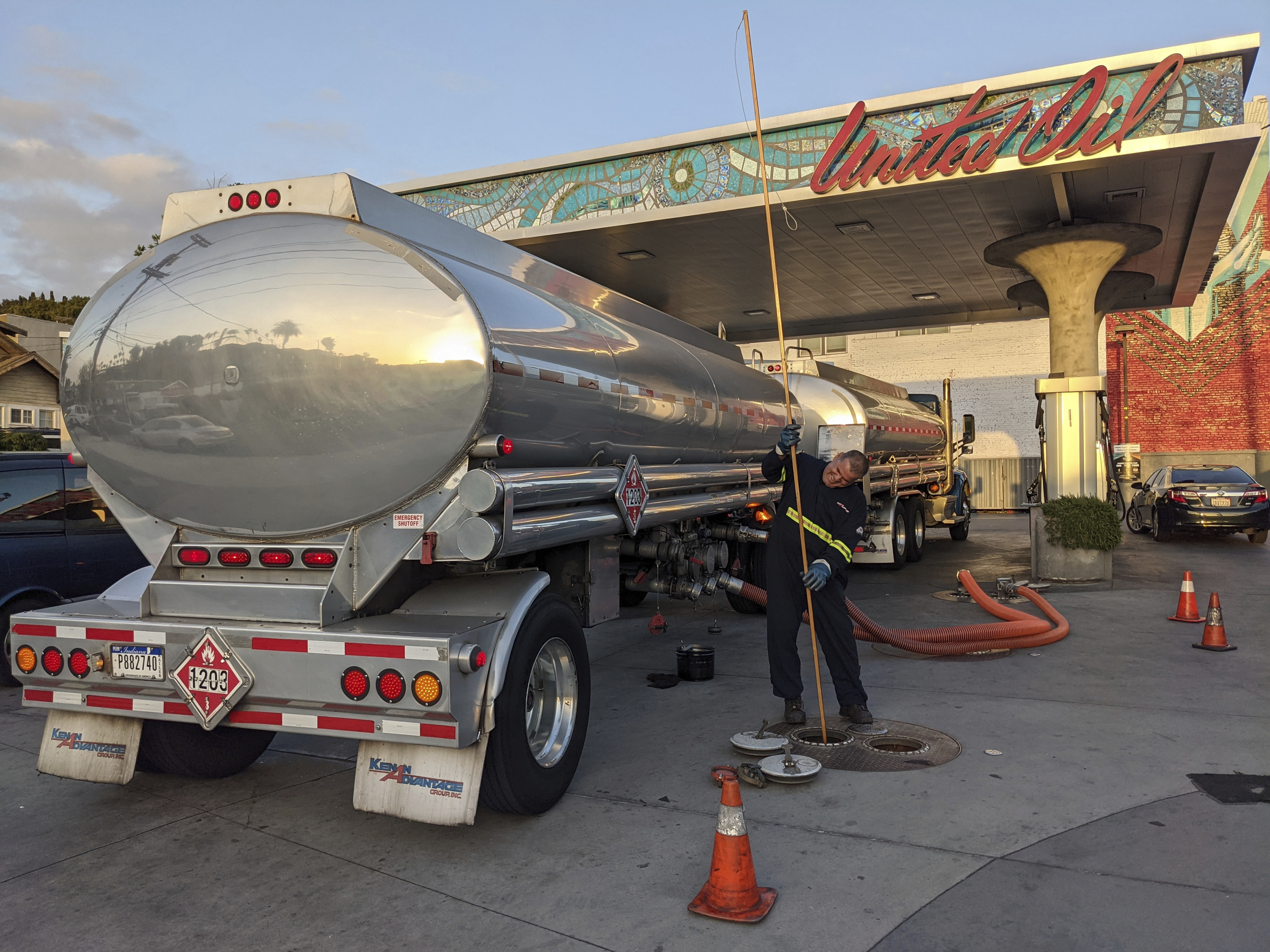 In this May 20, 2021 photo, a fuel truck driver checks the gasoline tank level at a United Oil gas station in Sunset Blvd., in Los Angeles. (AP Photo/Damian Dovarganes)