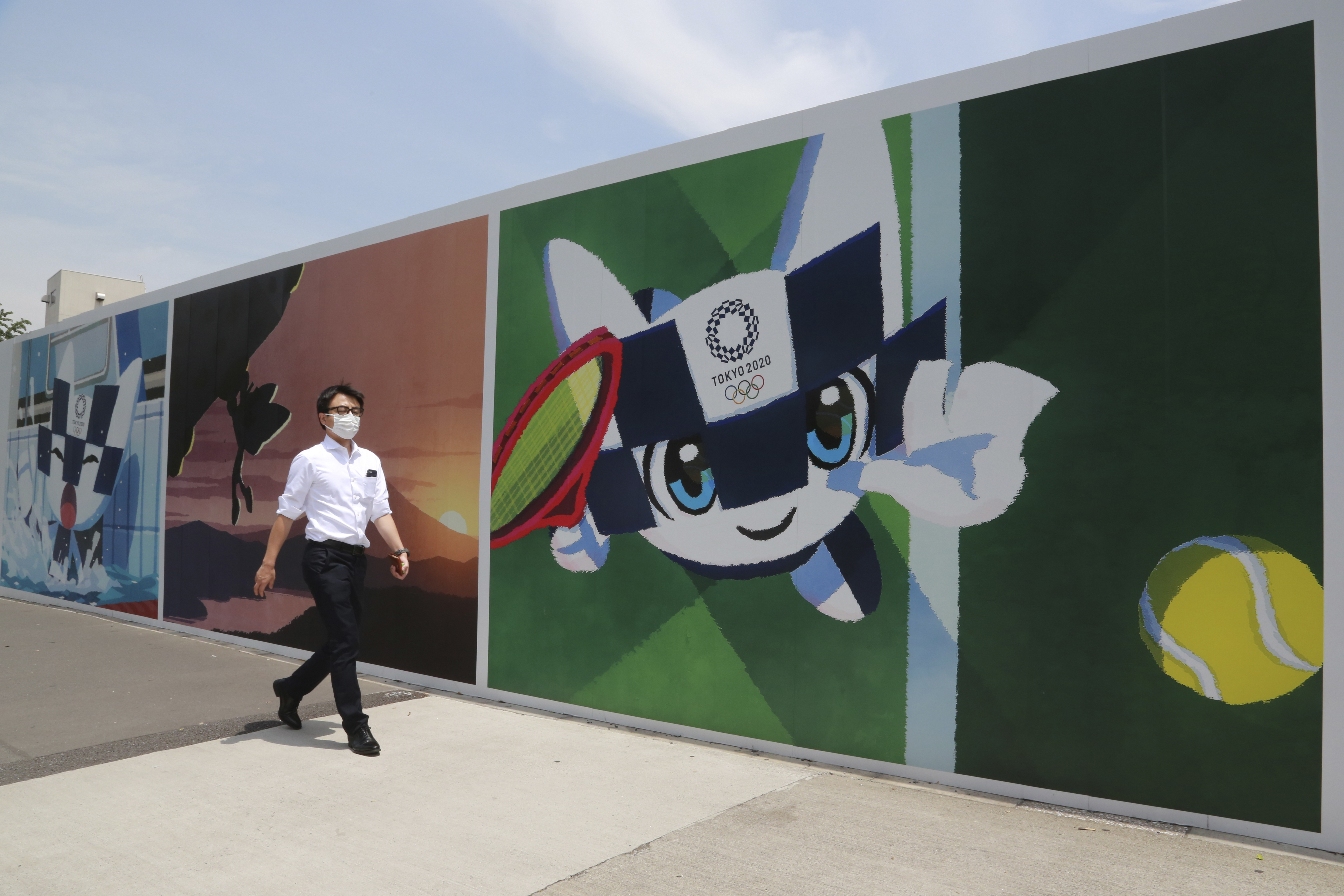 A man walks by posters promoting the Olympic Games planned to start in the summer of 2021, in Tokyo, Monday, May 24, 2021. (AP Photo/Koji Sasahara)