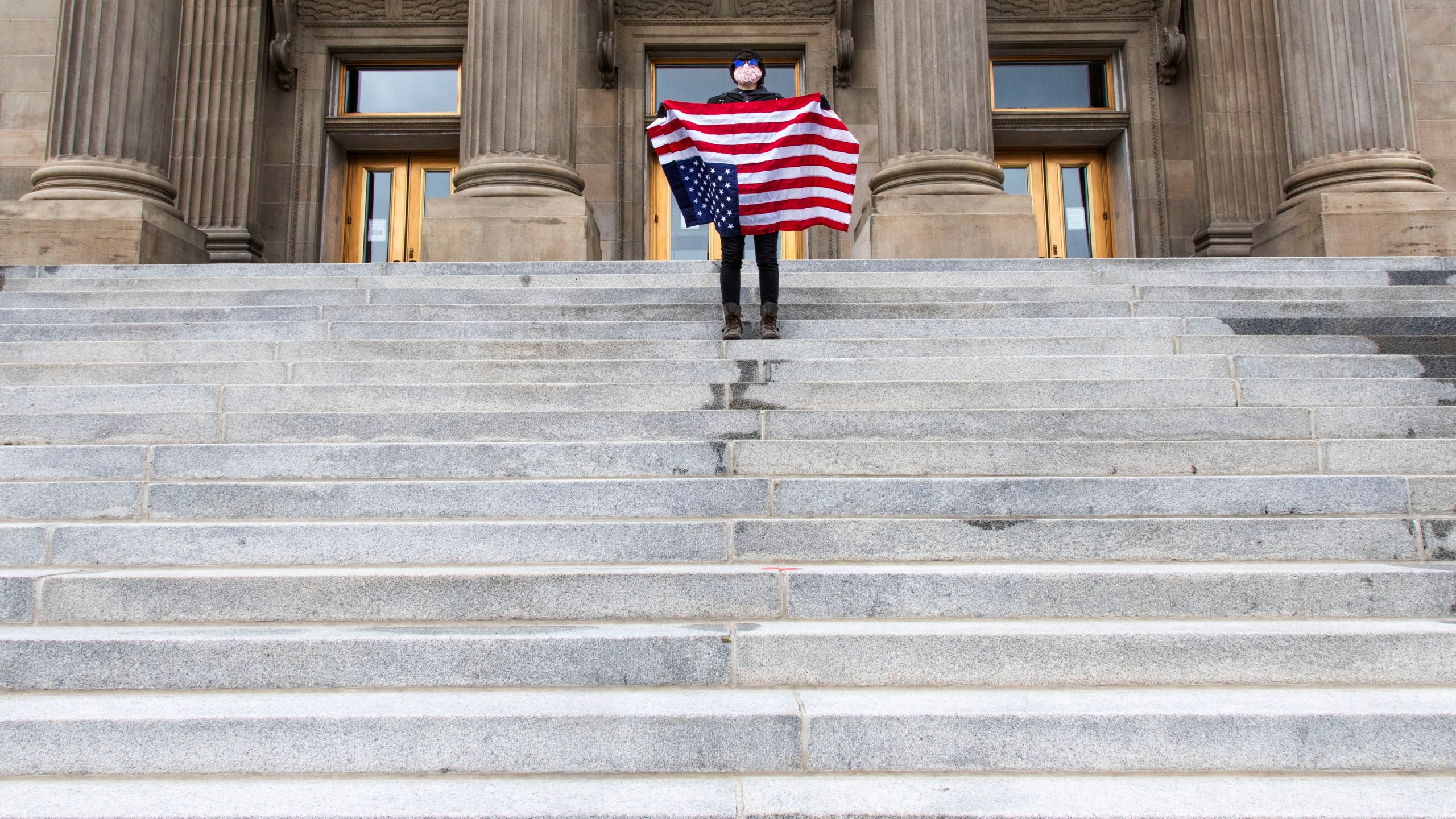 In this April 26, 2021, file photo, a student holding a U.S. flag upside down stands atop the steps at the Idaho Capitol building in Boise. The Idaho Senate has approved legislation aimed at preventing schools and universities from "indoctrinating" students through teaching critical race theory, which examines the ways in which race and racism influence American politics, culture and the law. (Darin Oswald/Idaho Statesman via AP, File)