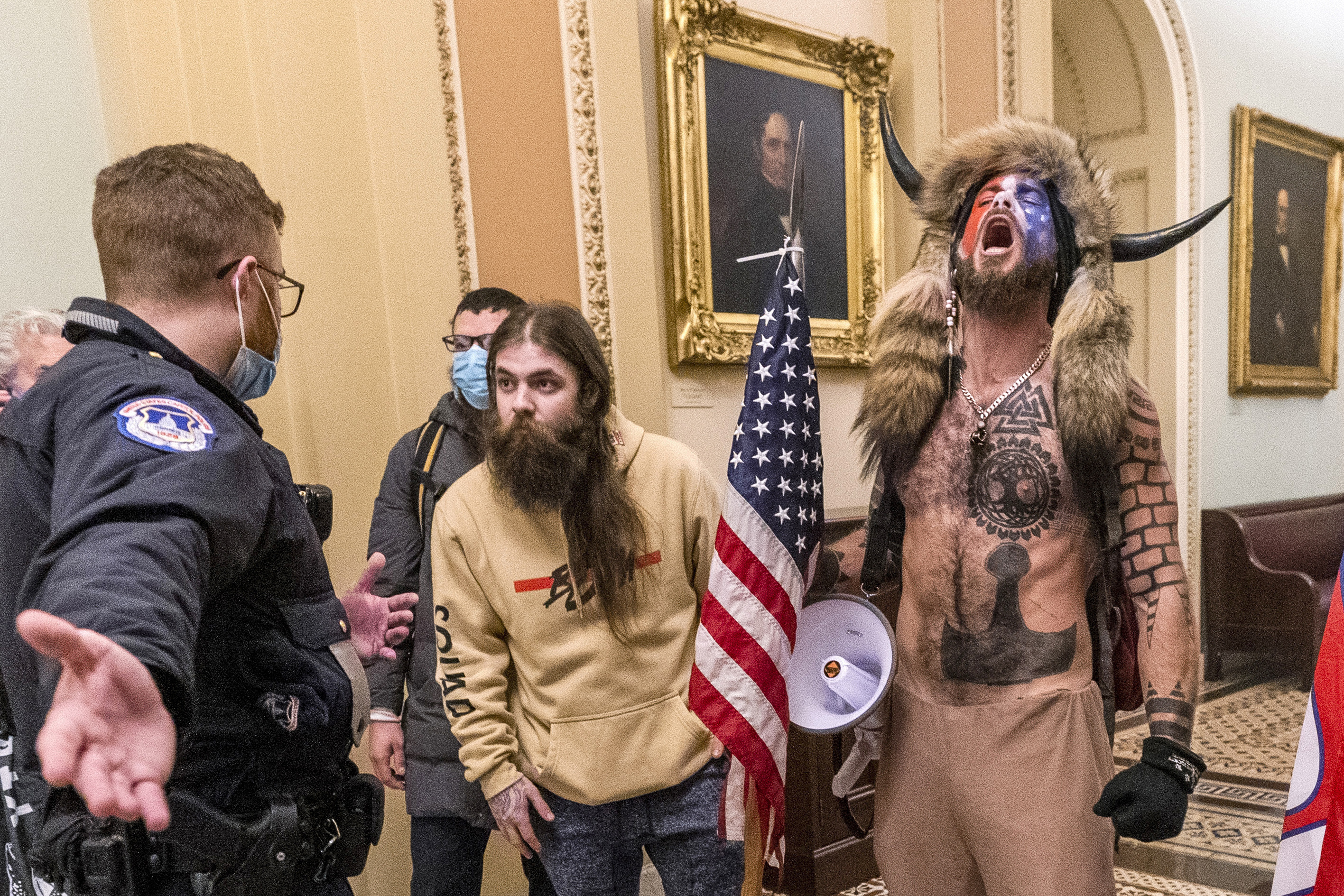 In this Jan. 6, 2021 file photo, supporters of President Donald Trump, including Jacob Chansley, right with fur hat, are confronted by U.S. Capitol Police officers outside the Senate Chamber inside the Capitol in Washington. Many of those who stormed the Capitol on Jan. 6 cited falsehoods about the election, and now some of them are hoping their gullibility helps them in court. Albert Watkins, the St. Louis attorney representing Chansley, the so-called QAnon shaman, likened the process to brainwashing, or falling into the clutches of a cult. Repeated exposure to falsehood and incendiary rhetoric, Watkins said, ultimately overwhelmed his client's ability to discern reality. (AP Photo/Manuel Balce Ceneta, File)