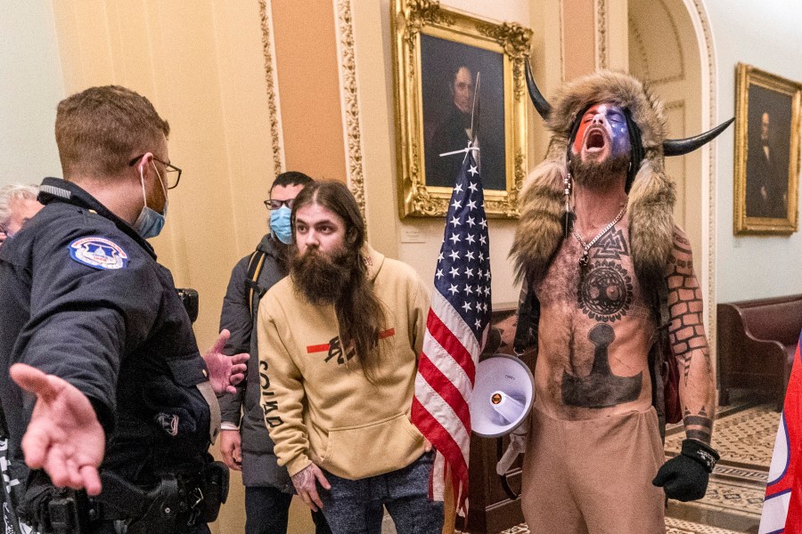 In this Jan. 6, 2021 file photo, supporters of President Donald Trump, including Jacob Chansley, right with fur hat, are confronted by U.S. Capitol Police officers outside the Senate Chamber inside the Capitol in Washington. Many of those who stormed the Capitol on Jan. 6 cited falsehoods about the election, and now some of them are hoping their gullibility helps them in court. Albert Watkins, the St. Louis attorney representing Chansley, the so-called QAnon shaman, likened the process to brainwashing, or falling into the clutches of a cult. Repeated exposure to falsehood and incendiary rhetoric, Watkins said, ultimately overwhelmed his client's ability to discern reality. (AP Photo/Manuel Balce Ceneta, File)