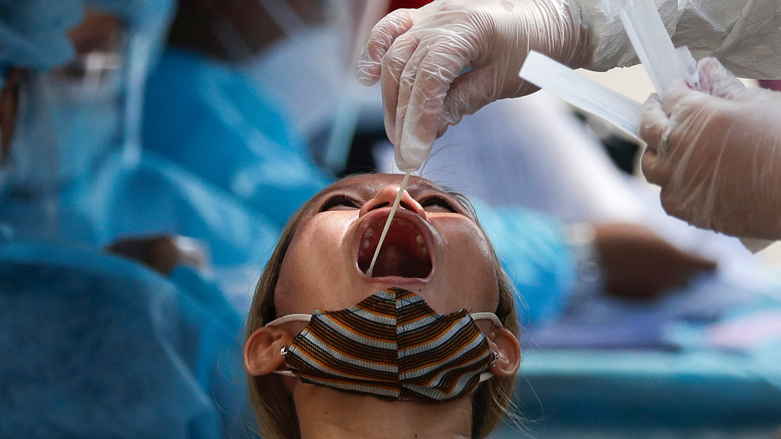 A health worker conducts a COVID-19 swab test on a resident as they monitor cases at a village in Quezon City, Philippines on Monday, May 31, 2021. (AP Photo/Aaron Favila)