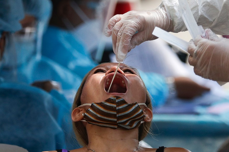 A health worker conducts a COVID-19 swab test on a resident as they monitor cases at a village in Quezon City, Philippines on Monday, May 31, 2021. (AP Photo/Aaron Favila)