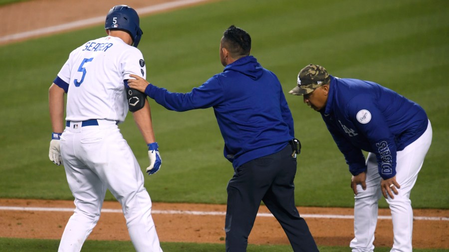 Corey Seager #5 of the Los Angeles Dodgers is helped by Dodgers medical staff after he was hit by a pitch, as Dave Roberts #30 looks on, during the fifth inning at Dodger Stadium on May 15, 2021 in Los Angeles. (Harry How/Getty Images)