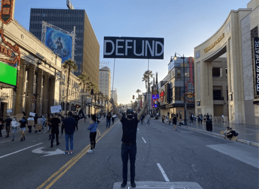 A protester holds up a sign calling for the Los Angeles Police Department to be defunded in Hollywood on June 7, 2020.(Kevin Rector / Los Angeles Times)