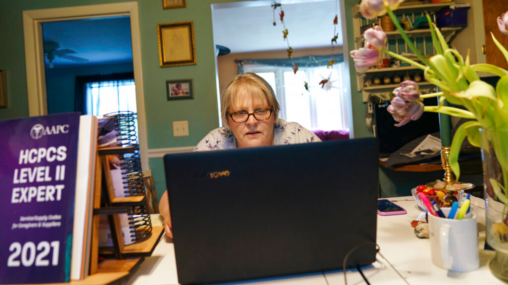 Ellen Booth, 57, studies at her kitchen table to become a certified medical coder, in Coventry, R.I., Monday, May 17, 2021. (AP Photo/David Goldman)