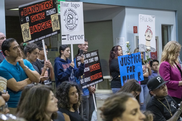 East Los Angeles residents, activists and relatives of people shot by deputies hold signs while attending the Sheriff Civilian Oversight Commission town hall in 2019. (Allen J. Schaben / Los Angeles Times)