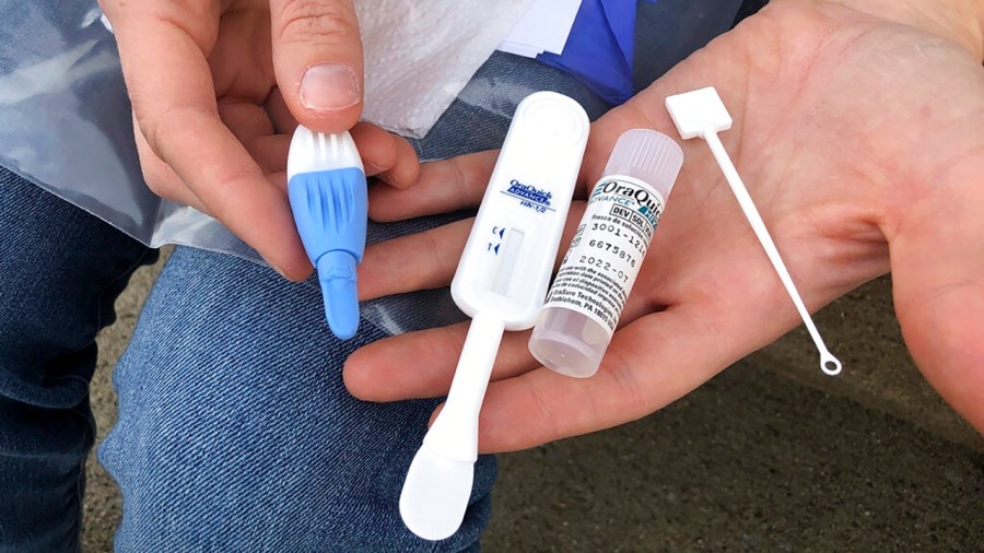 In this Tuesday, March 9, 2021 file photo, Solutions Oriented Addiction Response organizer Brooke Parker holds an HIV testing kit in Charleston, W.Va. The nonprofit group operates health fairs for residents, including syringe exchanges and HIV testing. Some researchers believe COVID-19 has derailed the fight against HIV, siphoning away health workers and other resources and setting back a U.S. campaign to decimate the AIDS epidemic by 2030. (AP Photo/John Raby)